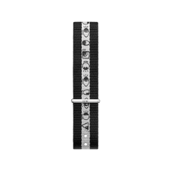 Black and white NATO watch strap from the Steven Harrington x Daniel Wellington set, featuring a central stripe with distinctive character motifs and a silver buckle.