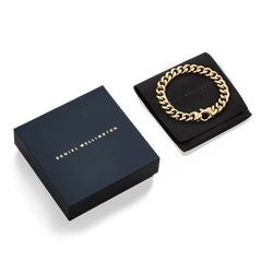 Ellipse Cuban Chain Bracelet Gold displayed on a black presentation pouch next to a navy Daniel Wellington gift box, highlighting its polished gold links and elegant packaging.