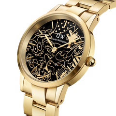 Limited edition Steven Harrington x DW Iconic Link Dual Tone watch with a gold stainless steel bracelet and a black dial featuring bold, artistic illustrations in gold detail.