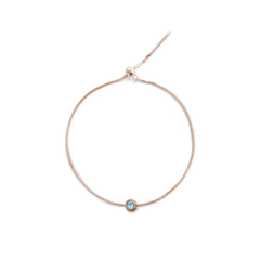 Rose gold bracelet featuring the December Charm with a central blue crystal, set on a slim adjustable chain for a refined and elegant finish.