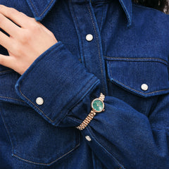 A woman wears the Elan Lumine Malachite Rose Gold watch with a green malachite dial and rose gold bracelet, styled with a dark denim shirt.