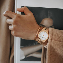 A person wearing the Daniel Wellington Iconic Link Rose Gold watch with a polished rose gold bracelet and minimalist white dial, styled alongside a matching rose gold bangle.