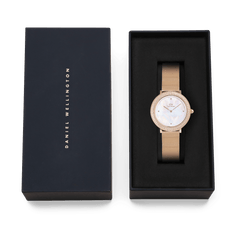 Crystalline Bezel Melrose women’s watch with a rose gold mesh strap and mother of pearl dial, elegantly presented in a black Daniel Wellington gift box.