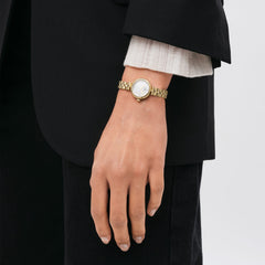 Woman wearing Elan Lumine Gold watch with gold bracelet and white crystal dial, styled with a black blazer.