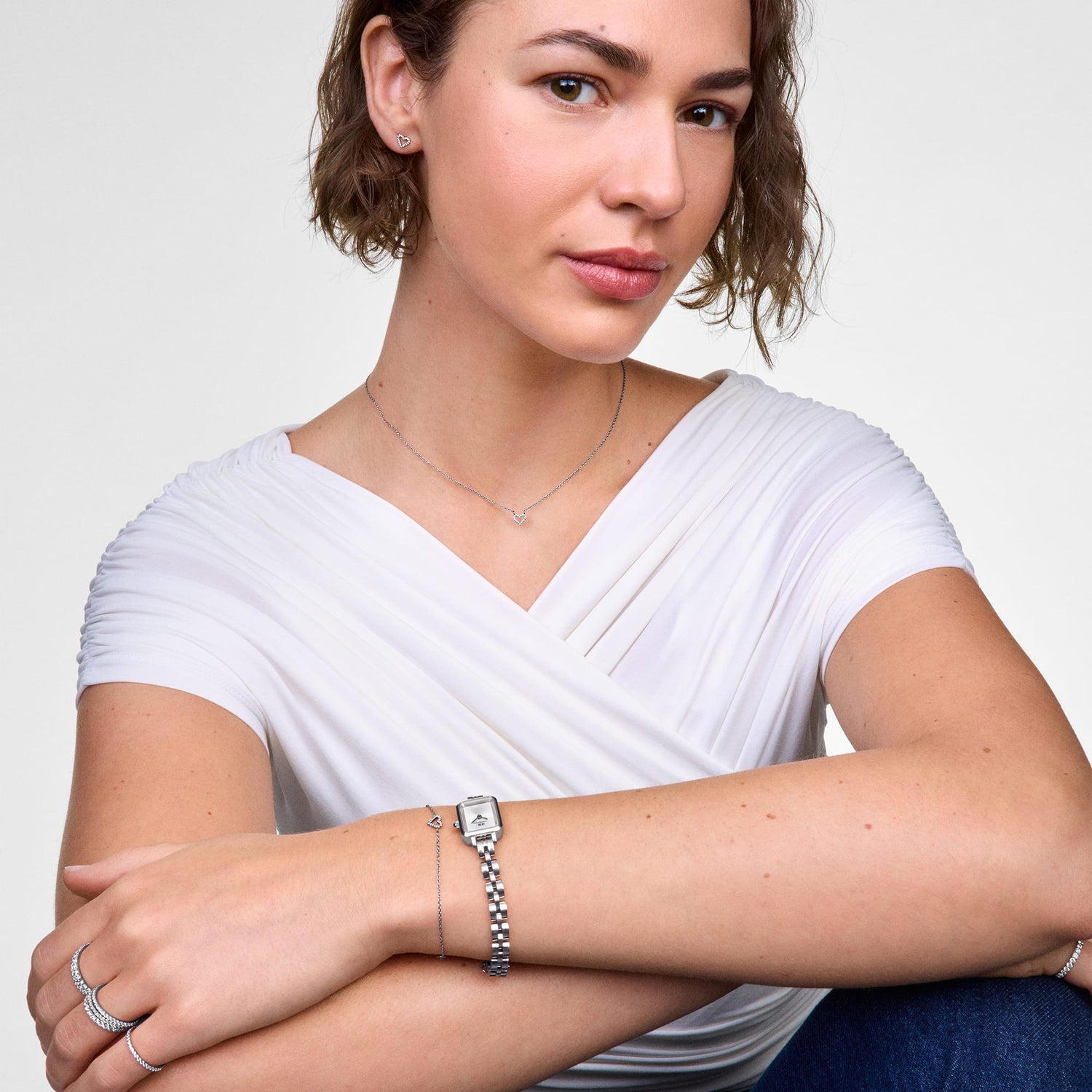 Woman wearing the Mirelle Heart Bracelet Silver on her wrist, styled alongside a silver watch and matching jewellery, highlighting the bracelet’s delicate open heart charm and minimalist design.