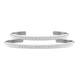Pair of Daniel Wellington classic silver open bangle bracelets, each crafted from polished stainless steel and engraved with the brand’s signature logo.