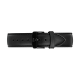 Black leather watch strap with a tapered design, featuring detailed stitching and an onyx black PVD-plated stainless steel buckle engraved with the Daniel Wellington logo. The strap has a smooth finish and a quick-release connector for easy attachment.