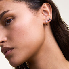 Woman wearing the Hoop + Heart + Flower Stud Silver Set, featuring a polished silver hoop, a heart stud, and a floral stud arranged along the ear for a modern, layered look.