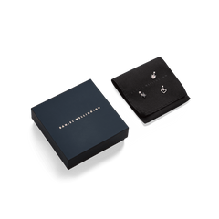 Daniel Wellington signature packaging displayed next to a black jewellery pouch holding three rose gold charms, ideal for gifting.