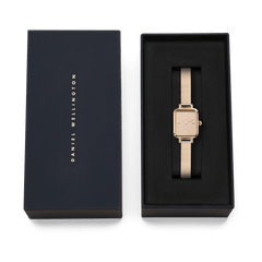 Quadro Mini Reflection Rose Gold watch with a rectangular mirror dial and rose gold mesh strap, elegantly presented in a black Daniel Wellington gift box.