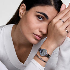 Woman wearing Petite Reflection Silver watch with mirror dial and mesh strap, styled with matching silver jewellery.