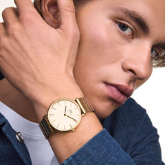 A person wearing the Classic Piano Link Gold Unitone watch, showcasing its brushed gold dial, minimalist face, and distinctive piano link bracelet styled with a casual denim shirt.
