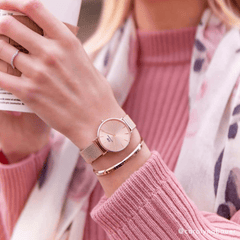 Woman wearing the Petite Melrose Light Pink watch with a rose gold mesh strap, styled alongside a matching bangle and a pink knit jumper.
