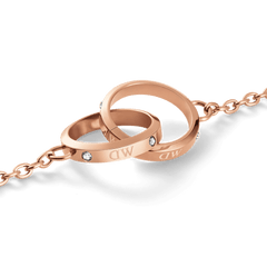 Close-up of the Classic Unity Lumine rose gold bracelet showing two intertwined rings with crystal accents and subtle engraved logotype on a delicate chain.