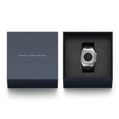 Daniel Wellington Switch Silver Apple Watch case with black rubber strap, presented in an elegant navy gift box with branded lid.