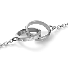 Close-up of the Classic Lumine Unity Silver necklace showing two interlocking polished silver rings engraved with DW and set with sparkling Preciosa crystals on a fine chain.