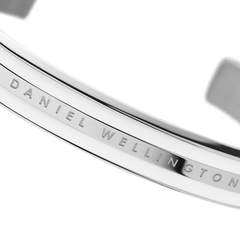 Detail view of the Daniel Wellington Emalie Bracelet showing the engraved logo on polished silver-tone stainless steel with satin white enamel.