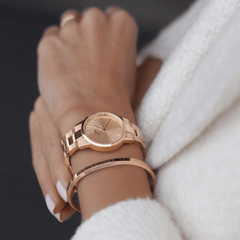 Woman wearing the Iconic Link Unitone Rose Gold watch with matching bracelet, styled with a white textured coat.
