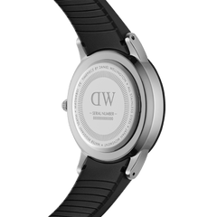 Close-up of the Daniel Wellington Iconic Motion watch showing the engraved stainless steel case back and black FKM rubber strap.