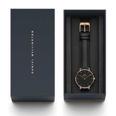 Daniel Wellington Petite Sheffield watch with a black leather strap and rose gold case, elegantly presented in a branded gift box.