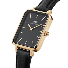 Elegant women’s watch featuring a rectangular black dial, polished gold-tone case, minimalist gold markers, and a black leather strap.