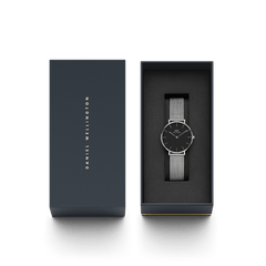 Petite Sterling women’s silver mesh watch with black dial, presented in Daniel Wellington gift box, perfect for gifting.