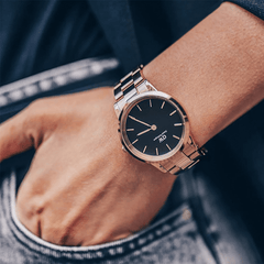 Daniel Wellington Iconic Link Rose Gold watch with black dial and link bracelet, styled on wrist with casual denim.