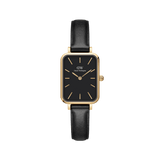 Rectangular gold women’s watch with a black dial, minimalist gold hour markers and hands, and a black leather strap.