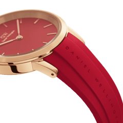 Close-up of the Daniel Wellington Iconic Motion Ruby watch showing the rose gold case, bold red dial, and embossed ruby red FKM rubber strap.