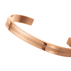 Close-up of the Daniel Wellington Elan Bracelet in rose gold, showing its polished open cuff design and subtle engraved logo.