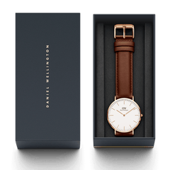 Classic St Mawes Rose Gold watch with brown leather strap, presented in a navy Daniel Wellington gift box.